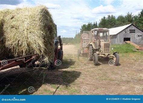 Russian Farm Tractor Moves Round Bales Of Hay Near Barn Editorial