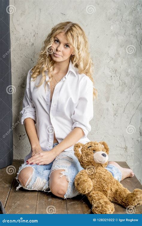 Blonde Hermoso Joven De La Muchacha En Una Camisa Blanca Y Vaqueros Con Huecos Foto De Archivo