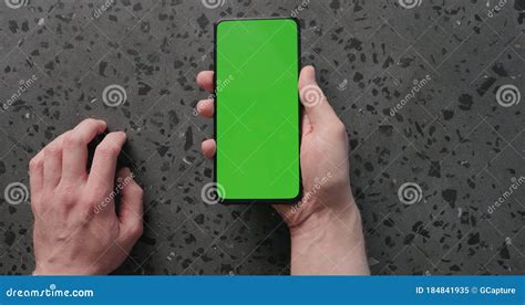 Top View Man Hand Use Smartphone With Green Screen On Concrete