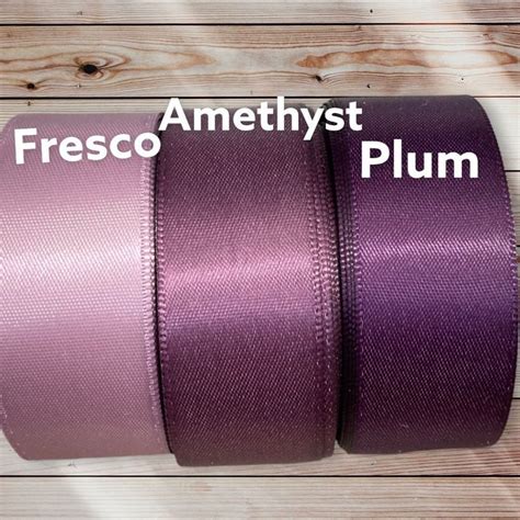 Three Rolls Of Purple Ribbon On Wooden Background With Text That Reads