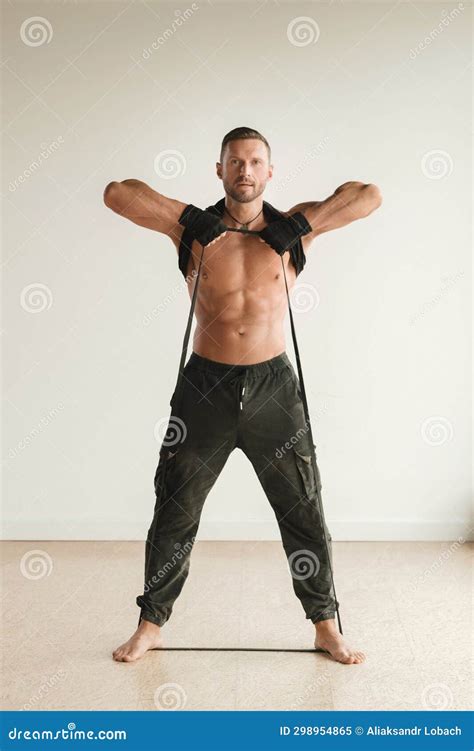 A Man With A Naked Torso Is Engaged In Strength Fitness Using A Rubber