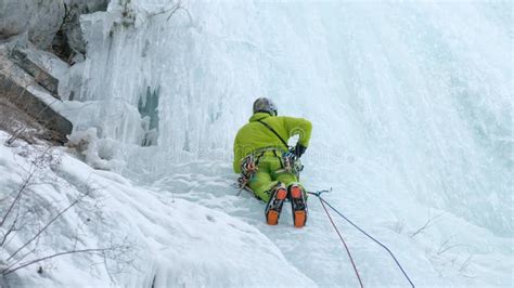 Alpinist Man With Ice Tools Axe Climbing A Frozen Waterfall A Large