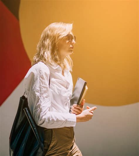 Blonde Jeune Femme Marchant Avec Des Journaux Intimes à La Main Photo Gratuite