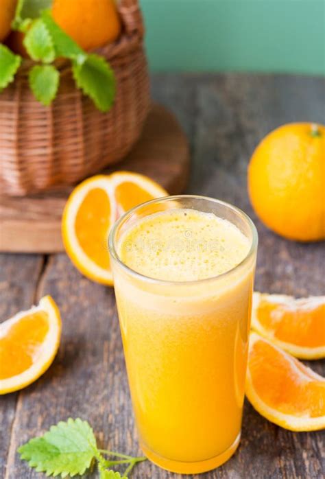 A Glass Of Freshly Squeezed Orange Juice Stands On A Wooden Table