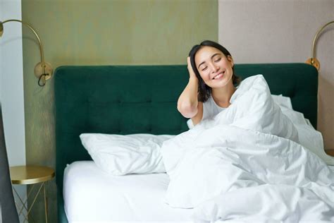 Happy Korean Woman Wakes Up In Her Hotel Room Lying In Bed Under Cozy