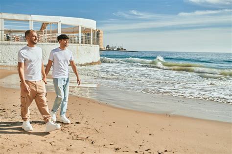 Joven Pareja Gay Sonriendo Feliz Caminando En La Playa Imagen De Archivo Imagen De Ocasional