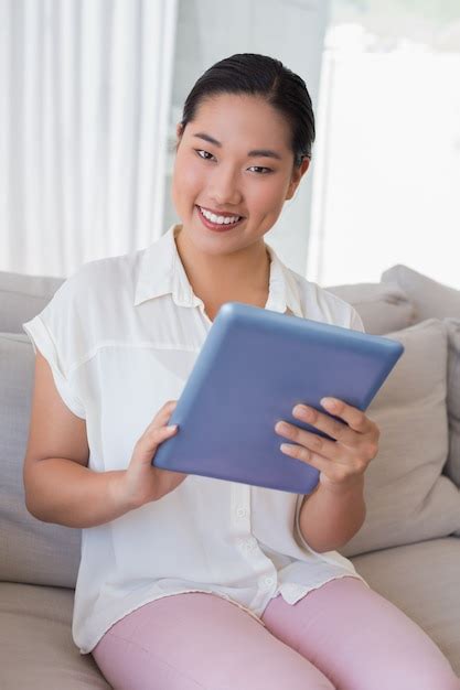 Premium Photo Smiling Woman Sitting On Couch Using Tablet Pc