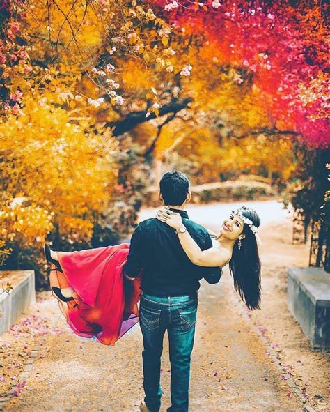 A Man Carrying A Woman On His Back While Walking Down A Path In The Fall