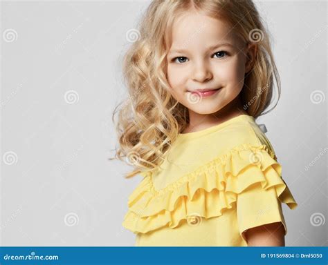 Portrait De Belle Fille Bouclée Blonde à La Robe Jaune à Regarder La Caméra Et Le Sourire Photo