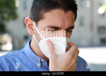 A man sneezing into protective mask against transmissible infectious ...