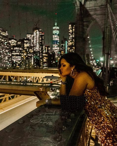 a woman sitting at a table in front of a cityscape with the lights on