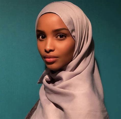 A Woman Wearing A Headscarf And Posing For A Photo In Front Of A Blue