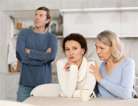 Man Is Actively Quarreling With His Thinking Wife In Kitchen Standing