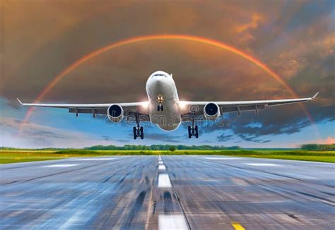 Passenger Airplane Landing At Sunset Rainbow On A Runway Stock Photo