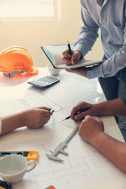 Premium Photo Midsection Of Engineers Working Over Plan In Office