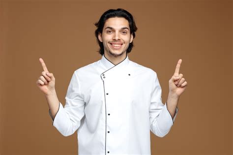 Sorrindo jovem chef masculino vestindo uniforme olhando para a câmera