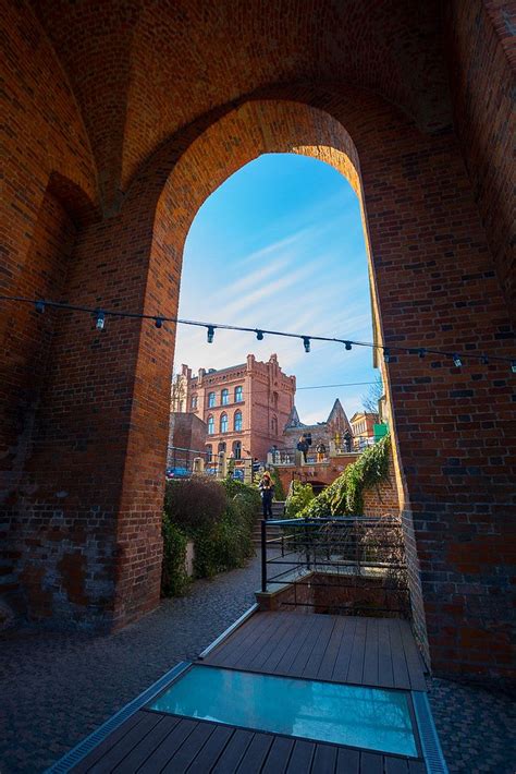 An Arched Brick Wall With Lights Hanging From It S Sides And A Walkway