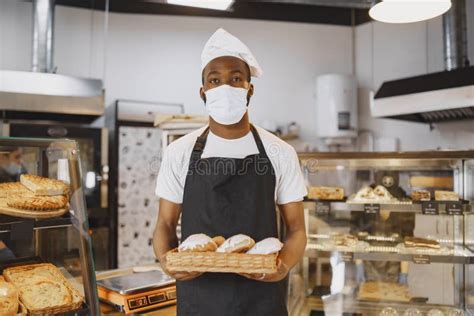 African American Baker Holding Tray Of Bread In Bakery Stock Photo