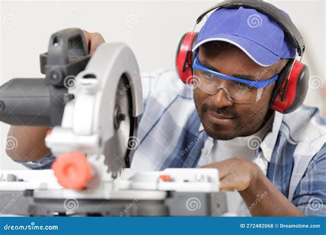 Skilled Woodworker Wearing Safety Gear Using Mitre Saw Stock Photo