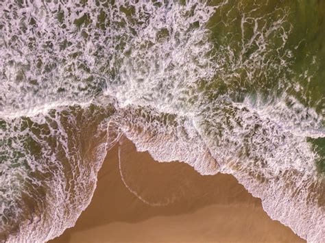 Vista aérea de arriba hacia abajo en una playa de arena con olas de mar