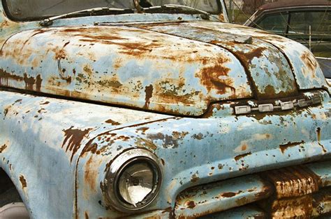 An Old Rusty Blue Truck Parked In A Parking Lot