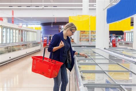 Chica de 30 años eligiendo comida congelada en el supermercado Foto