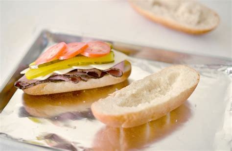 a sandwich with pickles, cheese and tomatoes on it sitting on a silver tray