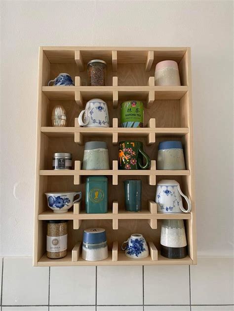 A Shelf Filled With Cups And Mugs On Top Of A White Tiled Floor Next To