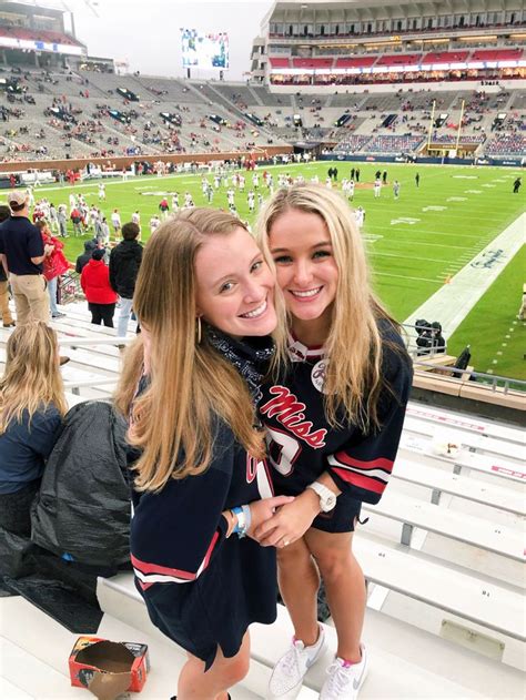 Two Girls Are Posing For A Photo In The Stands At A Football Game One