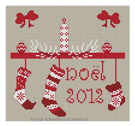 A Cross Stitch Christmas Stocking With Stockings Hanging From It S