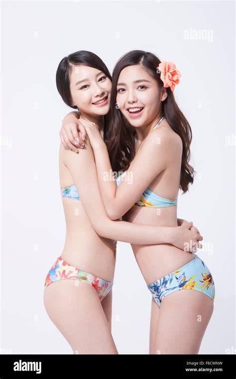 Two Women In Bikini Hugging Each Other And Staring Forward With A Smile