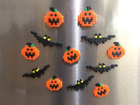 Six Perler Beads Arranged In The Shape Of Pumpkins On A Metal Surface