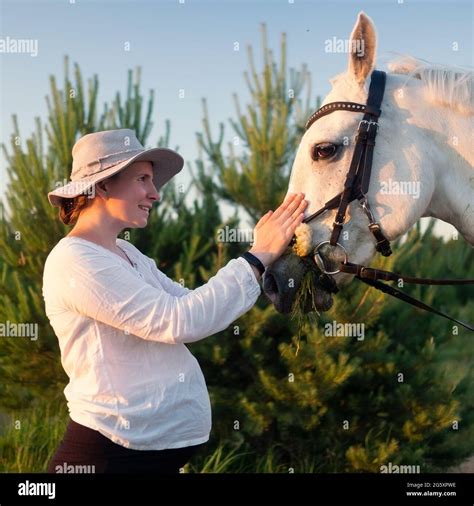 Young Pregnant Woman Feeding A White Horse In The Field Stock Photo Alamy