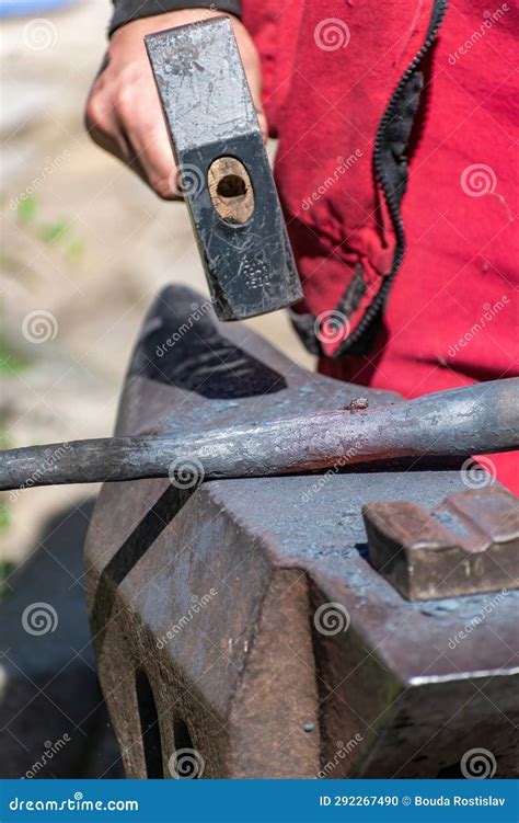 A Blacksmith Working A Piece Of Iron While Working On An Anvil Stock