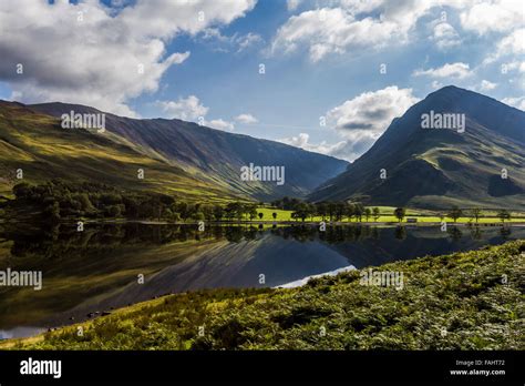 Lake Buttermere Reflecting The Surrounding Hills On A Bright Sunny