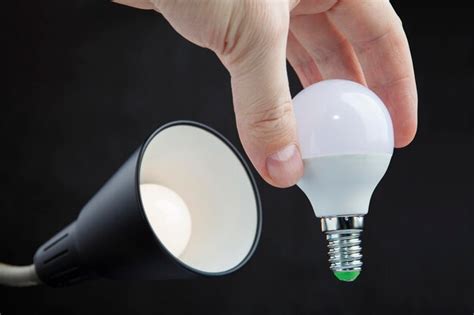 Premium Photo Cropped Hand Of Person Holding Light Bulb Against Black