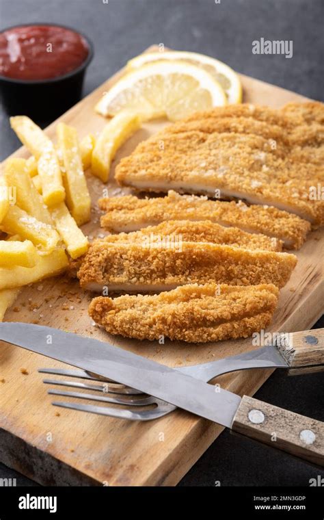 Wiener schnitzel with fried potatoes on black background Stock Photo - Alamy