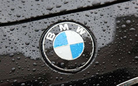 The BMW logo on a black car with raindrops Wallpaper Download 5120x3200