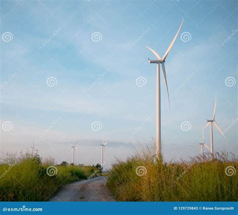 Wind Turbine In Grass Field With Dirt Road And Blue Sky Stock Image