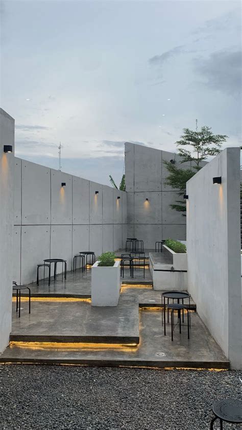 An Outdoor Seating Area With Tables And Chairs In Front Of A Concrete