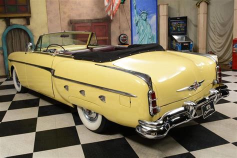 an old yellow car is parked in a room with black and white checkered ...