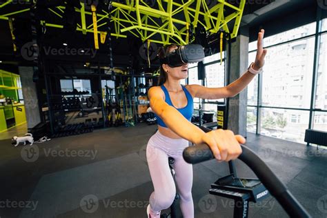 Beautiful brunette on an exercise bike in virtual reality glasses ...