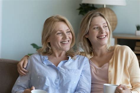 Cheerful Senior Mother And Adult Daughter Sitting On Sofa Together