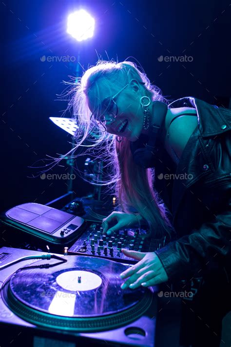 Happy Blonde Dj Girl Touching Vinyl Record And Smiling In Nightclub