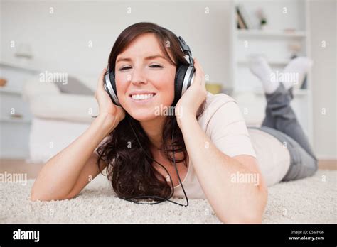 Glad Brunette Woman Using Headphones While Lying On A Carpet Stock Photo Alamy