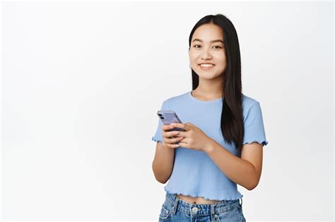 Tecnologia celular Menina asiática sorridente segurando smartphone e