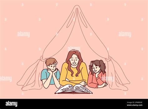 Nanny And Two Small Children Reading Book Lying On Floor In Tent