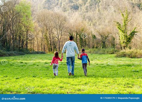 Father With Children Walking Out Of Town Through The Countryside