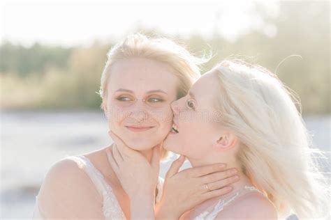 Beautiful Lesbian Couple Walking On Sand Along River Bank On Their Wedding Day Stock Image