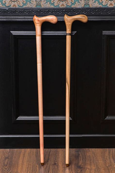 Two Wooden Walking Canes Sitting On Top Of A Hard Wood Floor Next To A Wall